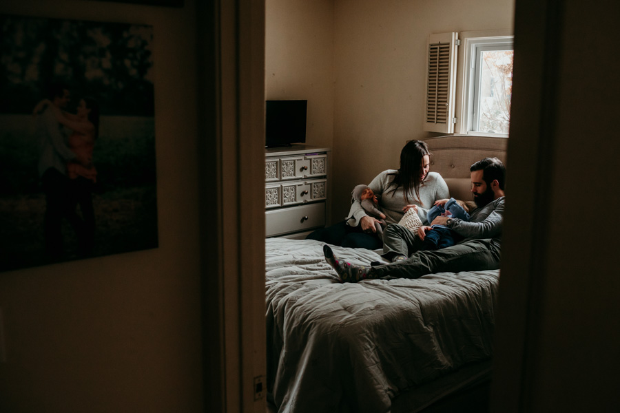 Photo of a family cuddling on their bed, shot from the hallway