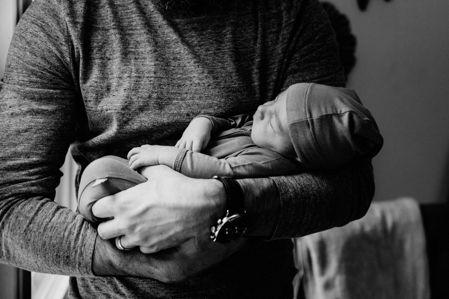 tiny newborn baby in his dad's arms, black and white